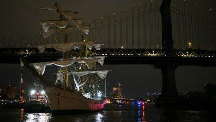 People gather to look at a Mexican Navy training ship near the Manhattan Bridge after it slammed into the nearby Brooklyn Bridge in New York on May 17, 2025. A Mexican Navy training ship slammed into the Brooklyn Bridge late Saturday, snapping all three of its masts and igniting a rescue operation beneath the iconic New York City landmark. At least 22 people were wounded, three of them critically, when the Cuauhtemoc, a barque built in 1982, slammed into the Brooklyn Bridge in New York City on Saturday, the navy said in a statement. (Photo by ANGELA WEISS / AFP)