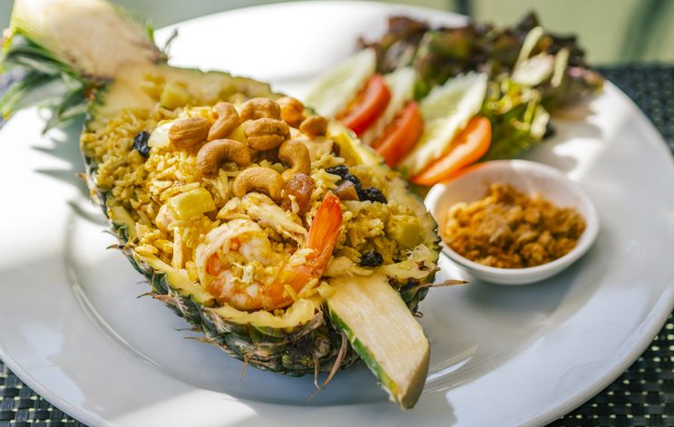 Pineapple fried rice with shrimps, Thai food popular santapan of fried rice, beautiful food decoration, serve fried rice in half fresh pineapple, cashew nuts on top. Close up food image, natural lighting.