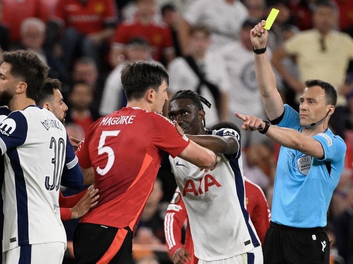 German referee Felix Zwayer presents a yellow card to Manchester United's English defender #05 Harry Maguire as he confronts Tottenham Hotspur's Malian midfielder #08 Yves Bissouma during the UEFA Europa League final football match between Tottenham Hotspur and Manchester United at San Mames stadium in Bilbao on May 21, 2025. (Photo by Josep LAGO / AFP)