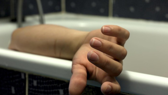 Dead body of woman in the bathroom in bath closeup on hand