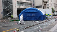 Petugas forensik bekerja di dekat lokasi kejadian saat sebuah mobil menabrak kerumunan penggemar Liverpool saat parade merayakan gelar juara Liga Primer Inggris, di pusat kota Liverpool, Inggris, Selasa (27/5/2025). (REUTERS/Phil Noble)