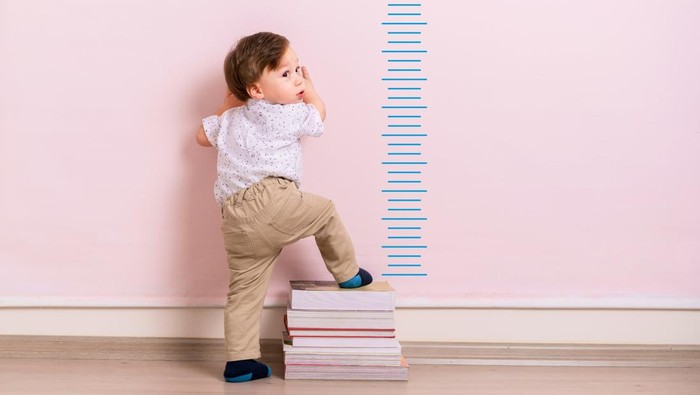 875205958 Child measuring his height on wall. He is growing up so fast.