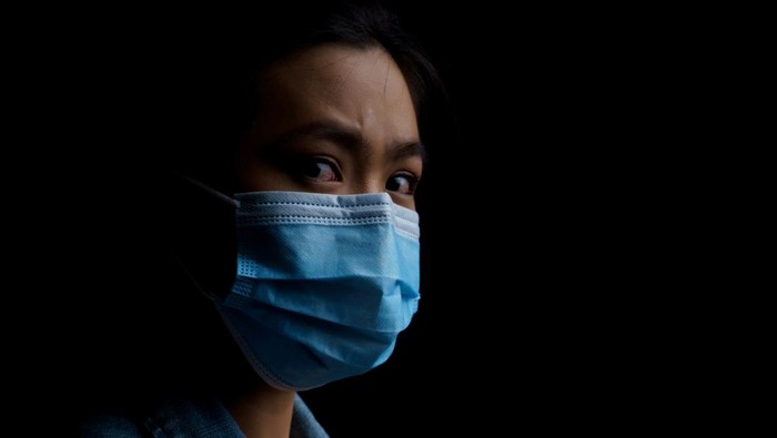 1272577247 Asian woman wearing protective mask isolated on background. Low key.