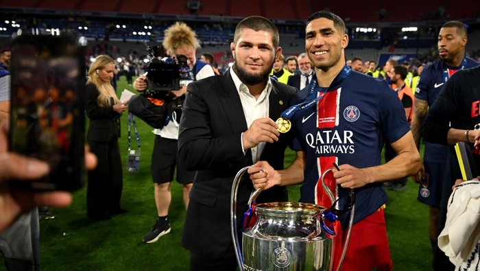 khabib nurmagomedov final liga champions psg vs inter milan paris saint-germain psg juara liga champions MUNICH, GERMANY - MAY 31: Achraf Hakimi of Paris Saint-Germain poses for a photograph with the UEFA Champions League trophy alongside former mixed martial artist Khabib Nurmagomedov after his teams victory, to secure Paris Saint-Germains first ever UEFA Champions League title in the clubs history and a record UEFA Champions League Final winning scoreline of 5-0, following the UEFA Champions League Final 2025 between Paris Saint-Germain and FC Internazionale Milano at Munich Football Arena on May 31, 2025 in Munich, Germany. (Photo by Michael Regan - UEFA/UEFA via Getty Images)