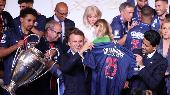 French President Emmanuel Macron holds a PSG jersey âChampions of Europe 2025â  with PSG president  Nasser Al-Khelaifi, while captain Marquinhos carries the cup after the team won the Champions League selesai soccer match between Paris Saint-Germain and Inter Milan, June 1, 2025 at the Elysee Palace in Paris, France. Thomas Padilla/Pool via REUTERS
