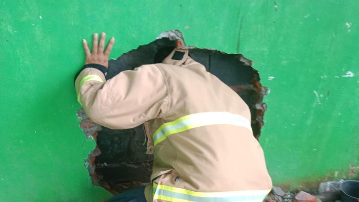 Seorang lansia di Gresik terjebak di celah sempit tembok rumah tetangganya.