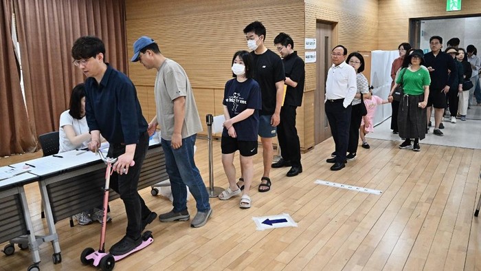 Warga Korsel mengantre untuk memakai hak suaranya dalam pilpres pada Selasa (3/6) waktu setempat People queue to vote at a polling station during the presidential election in Seoul on June 3, 2025. (Photo by Pedro Pardo / AFP)