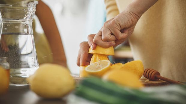 Close-up shot of a woman squeezing juice and making lemonade in the kitchen.
