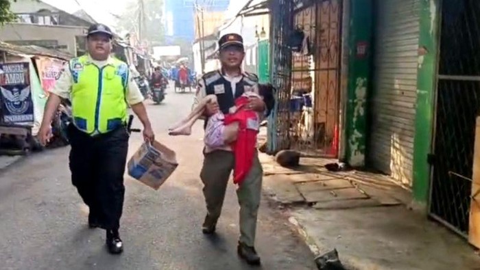 Satpol PP Kebayoran Lama mengamankan seorang anak yang disangka  disiksa oleh orang tuanya di Pasar Kebayoran Lama, Jakarta Selatan, Rabu (11/6/2025).