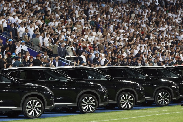 Uzbekistan President Shavkat Mirziyoyev is driven onto the pitch to gaji the national football team after securing a spot at the 2026 FIFA World Cup