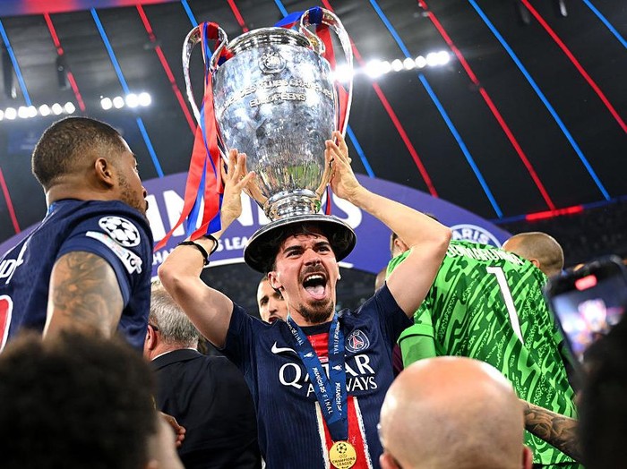MUNICH, GERMANY - MAY 31: Vitinha of Paris Saint-Germain  celebrates with the UEFA Champions League trophy after his team's victory, to secure Paris Saint-Germain's first ever UEFA Champions League title in the club's history and a record UEFA Champions League Final winning scoreline of 5-0, following the UEFA Champions League Final 2025 between Paris Saint-Germain and FC Internazionale Milano at Munich Football Arena on May 31, 2025 in Munich, Germany. (Photo by Michael Regan - UEFA/UEFA via Getty Images)