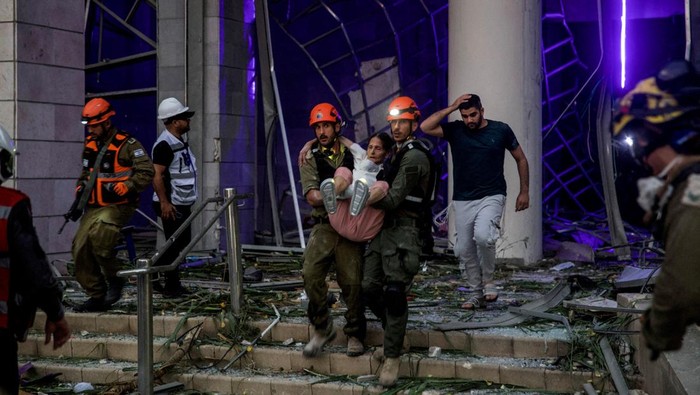 Rentetan Rudal Iran Sukses Hancurkan Kota-kota Israel Rescuers evacuate an injured woman from an impacted residential building following a missile attack from Iran on Israel, central Israel, June 16, 2025. REUTERS/Itay Cohen TPX IMAGES OF THE DAY