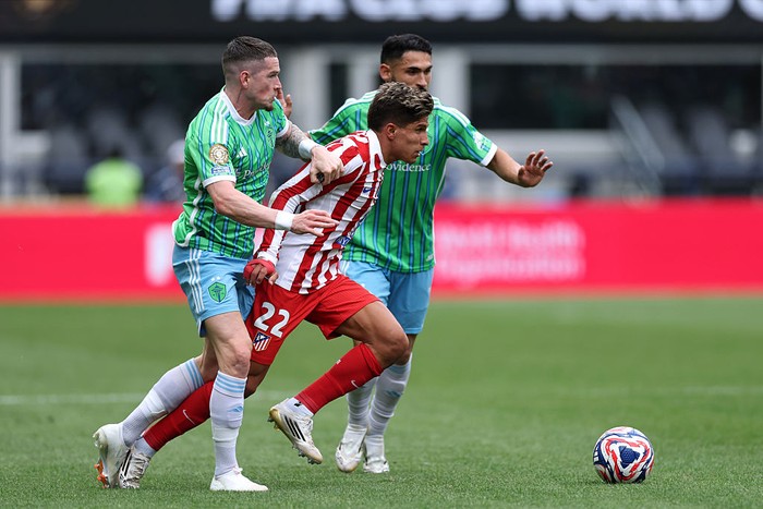 SEATTLE, WASHINGTON - JUNE 19: Giuliano Simeone #22 of Atletico De Madrid is held back by Ryan Kent #77 and Cristian Roldan #7 of Seattle Sounders FC during the FIFA Club World Cup 2025 group B match between Seattle Sounders FC and Club Atletico de Madrid at Lumen Field on June 19, 2025 in Seattle, Washington. (Photo by Buda Mendes/Getty Images)