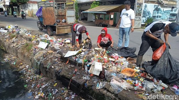 Petugas membersihkan sampah awut-awutan yang meluber ke got di Jalan Mallengkeri, Makassar.