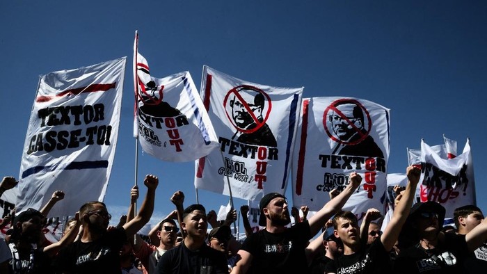 Members of Olympique Lyonnais ultra supporters wave flags in front of the Groupama Stadium, to support the team and ask for the clubs US president John Textors destitution, a few days after the relegation of the club in Ligue 2 on June 28, 2025 in Decines Charpieu. (Photo by JEFF PACHOUD / AFP)