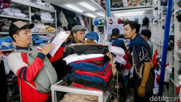 Orang tua bersama sang anak  memilih dan mencoba peralatan sekolah di kios perlengkapan sekolah di Pasar Kebayoran Lama, Jakarta, Jumat (11/7/2023). Menjelang tahun ajaran baru 2025/2026 penjualan berbagai jenis perlengkapan sekolah seperti baju seragam, tas, dan sepatu mengalami peningkatan dibandingkan dengan hari biasa.