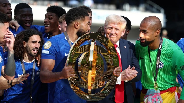 Momen Donald Trump Ogah Turun Podium, Ikut Pesta Juara Chelsea Chelsea's Reece James holds the trophy as he celebrates with teammates and U.S. President Donald Trump after Chelsea won against Paris St Germain in the FIFA Club World Cup final, at the MetLife Stadium in East Rutherford, New Jersey, U.S., July 13, 2025. REUTERS/Kevin Lamarque/Pool
