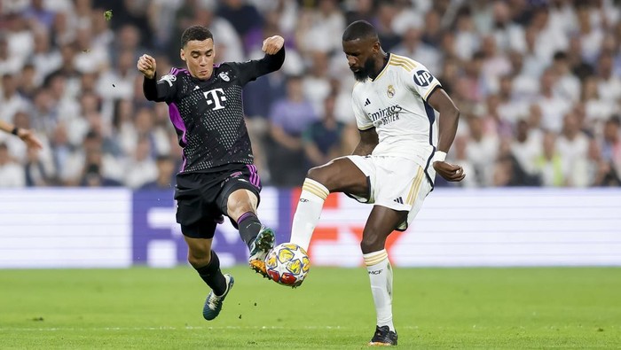 MADRID, SPAIN - MAY 8: Jamal Musiala (L) of Bayern Muenchen pressures Antonio Ruediger of Real Madrid for the ball during the UEFA Champions League semi-final second leg match between Real Madrid and FC Bayern München at Estadio Santiago Bernabeu on May 8, 2024 in Madrid, Spain. (Photo by Manuel Reino/DeFodi Images via Getty Images)