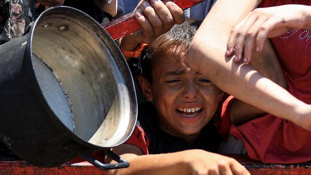 A Palestinian child reacts as he waits to receive food from a charity kitchen, amid a hunger crisis, in Gaza City, July 24, 2025. REUTERS/Dawoud Abu Alkas