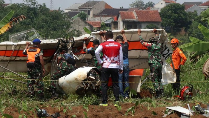 Petugas Basarnas bersama prajurit TNI AU berusaha mengevakuasi bangkai pesawat latih sipil Microlight Fixedwing Quicksilver GT500 dengan register PK-S126 yang jatuh di perkebunan warga, TPU Astana, Ciampea, Kabupaten Bogor, Jawa Barat, Minggu (3/8/2025). Pesawat latih sipil milik Federasi Aero Sport Indonesia (FASI) yang mengalami hilang kontak pada pukul 09.19 WIB ditemukan jatuh di sekitar TPU tersebut dan menyebabkan satu orang meninggal dunia dan satu orang mengalami luka berat dan dibawa ke RSAU dr. M. Hassan Toto, Bogor. ANTARA FOTO/Fadli/Arf/rwa.
