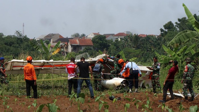 Petugas Basarnas bersama prajurit TNI AU berusaha mengevakuasi bangkai pesawat latih sipil Microlight Fixedwing Quicksilver GT500 dengan register PK-S126 yang jatuh di perkebunan warga, TPU Astana, Ciampea, Kabupaten Bogor, Jawa Barat, Minggu (3/8/2025). Pesawat latih sipil milik Federasi Aero Sport Indonesia (FASI) yang mengalami hilang kontak pada pukul 09.19 WIB ditemukan jatuh di sekitar TPU tersebut dan menyebabkan satu orang meninggal dunia dan satu orang mengalami luka berat dan dibawa ke RSAU dr. M. Hassan Toto, Bogor. ANTARA FOTO/Fadli/Arf/rwa.