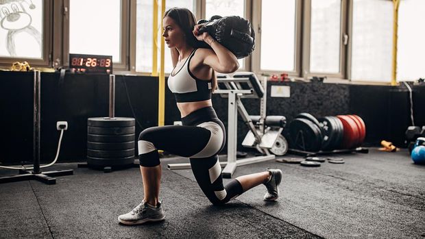One woman, fit young female training with weights alone in gym.