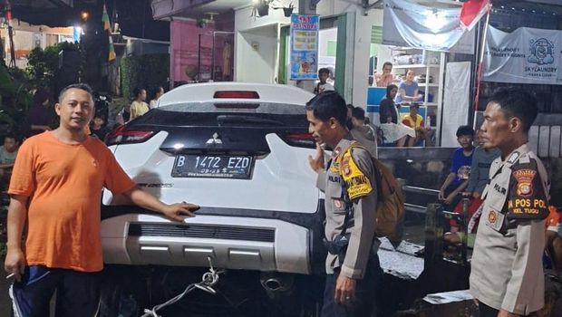 Warga membantu mengevakuasi mobil yang terseret banjir dan nyaris menyeret sekeluarga di Cimanggis, Depok.