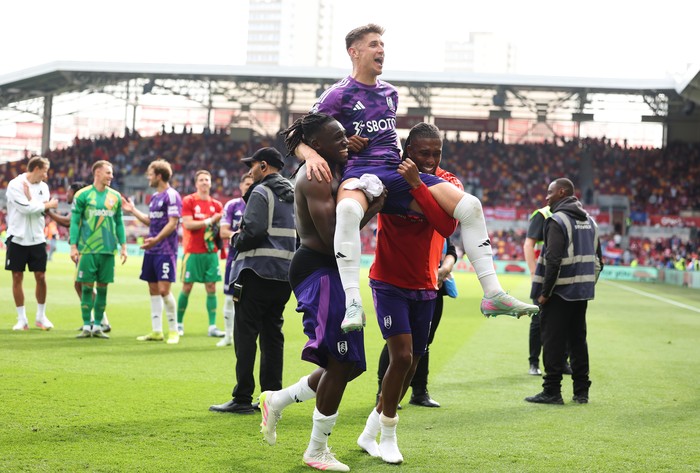 calvin bassey,fulham,premier league,liga inggris,celana kedodoran Tom Cairney is lifted by Calvin Bassey and Alex Iwobi of Fulham as they celebrate victory following the Premier League match between Brentford FC and Fulham FC at Gtech Community Stadium on May 18, 2025 in Brentford, England. (Photo by Alex Davidson/Getty Images)