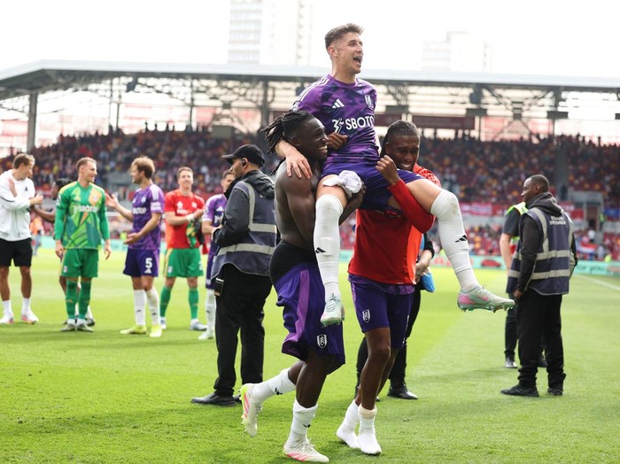 BRENTFORD, ENGLAND - MAY 18: Tom Cairney is lifted by Calvin Bassey and Alex Iwobi of Fulham as they celebrate victory following the Premier League match between Brentford FC and Fulham FC at Gtech Community Stadium on May 18, 2025 in Brentford, England. (Photo by Alex Davidson/Getty Images)