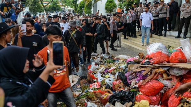 Anggota polisi berjaga saat sejumlah warga melakukan aksi buang sampah di depan pintu masuk Kantor Bupati Pandeglang, Pandeglang, Banten, Rabu (20/8/2025). Aksi yang diikuti sekitar 300 warga tersebut untuk memprotes kerja sama Pemerintah Kabupaten Pandeglang dan Pemerintah Kota Tangerang Selatan terkait penampungan sampah di TPA Bangkonol Pandeglang yang menimbulkan pencemaran lingkungan dan berdampak pada kesehatan masyarakat yang tinggal di sekitar TPA. ANTARA FOTO/Muhammad Bagus Khoirunas/tom.