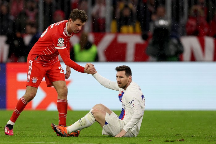 MUNICH, GERMANY - MARCH 08: Thomas Mueller of FC Bayern Munich helps up Lionel Messi of Paris Saint-Germain during the UEFA Champions League round of 16 leg two match between FC Bayern München and Paris Saint-Germain at Allianz Arena on March 08, 2023 in Munich, Germany. (Photo by Alexander Hassenstein/Getty Images)