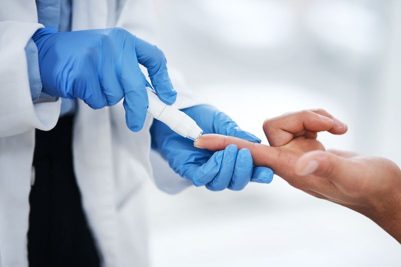 Shot of an unrecognisable doctor using a blood sugar test on his patient's finger
