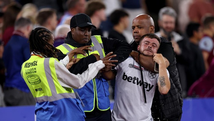 LONDON, ENGLAND - AUGUST 22: A West Ham United fan is escorted off the pitch by security during the Premier League match between West Ham United and Chelsea at London Stadium on August 22, 2025 in London, England. (Photo by Justin Setterfield/Getty Images)