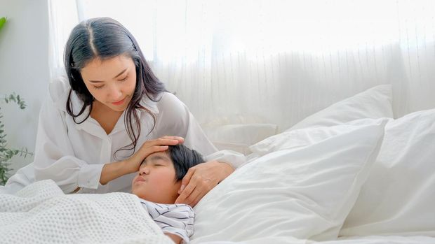 Asian mother take care her son during cold in bedroom with day light.