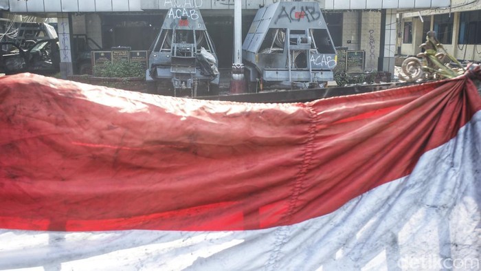 Markas Gegana di Jalan Kramat Raya hancur diamuk massa. Dua bus hangus masih terparkir di depan, sementara warga berkerumun menyaksikan kondisi bangunan, Sabtu (30/8/2025).