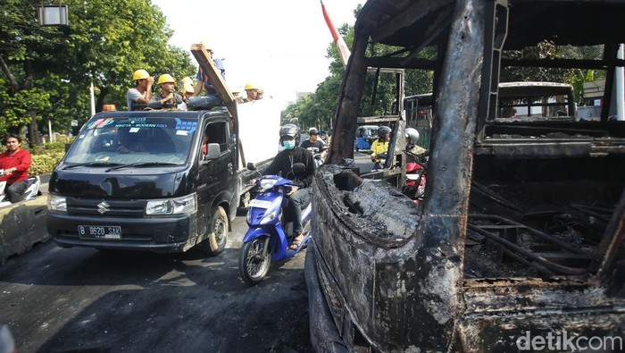 Markas Gegana di Jalan Kramat Raya hancur diamuk massa. Dua bus hangus masih terparkir di depan, sementara warga berkerumun menyaksikan kondisi bangunan, Sabtu (30/8/2025).