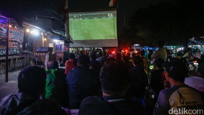 Sejumlah warga berkumpul menyaksikan laga Timnas Indonesia melawan Lebanon di Kawasan Pasar Gembrong, Jakarta, Senin (8/9/2025). Suasana meriah terlihat di sekitar lokasi meski pertandingan digelar jauh di Surabaya.