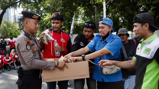 Polisi membagikan air mineral dan roti kepada massa buruh yang demo di Monas, Jakpus, Rabu (10/9/2025).