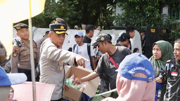 Polisi membagikan air mineral dan roti kepada massa buruh yang demo di Monas, Jakpus, Rabu (10/9/2025).