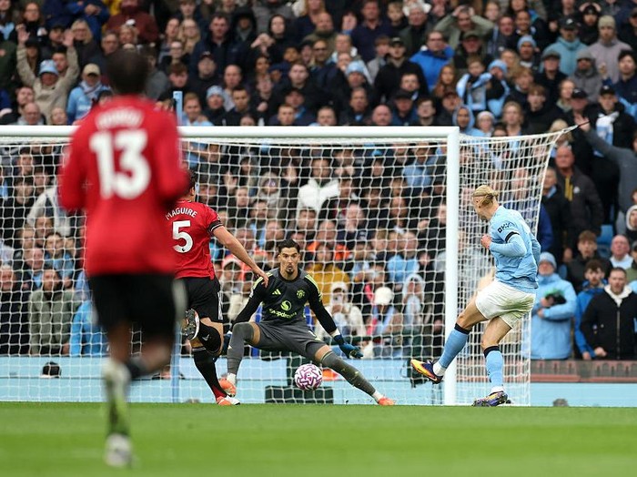 MANCHESTER, ENGLAND - SEPTEMBER 14: Erling Haaland of Manchester City scores his team's third goal past Altay Bayindir of Manchester United during the Premier League match between Manchester City and Manchester United at Etihad Stadium on September 14, 2025 in Manchester, England. (Photo by Carl Recine/Getty Images)