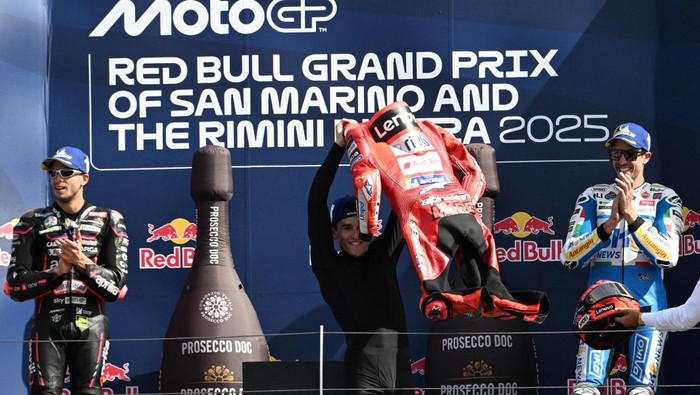 Marc Marquez mengangkat baju balapnya di podium usai juara MotoGP San Marino (Foto: REUTERS/Jennifer Lorenzini)