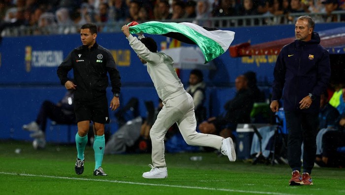 Barcelona vs Getafe, Bendera Palestina Soccer Football - LaLiga - FC Barcelona v Getafe - Johan Cruyff Stadium, Barcelona, Spain - September 21, 2025 General view of a pitch invader with a Palestine flag running past FC Barcelona coach Hansi Flick during the match REUTERS/Albert Gea