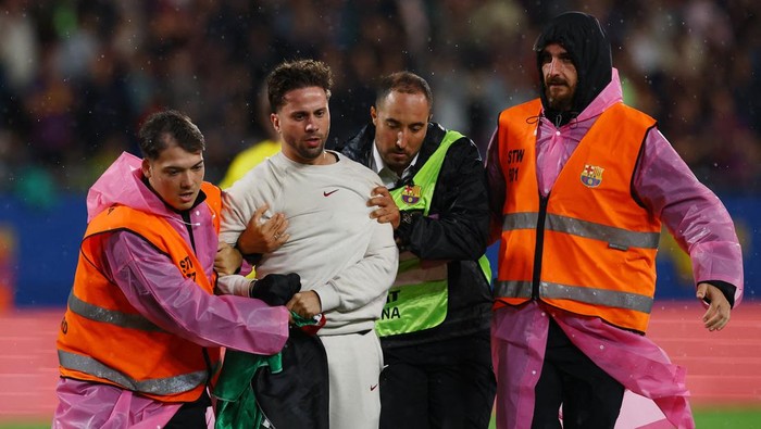 Soccer Football - LaLiga - FC Barcelona v Getafe - Johan Cruyff Stadium, Barcelona, Spain - September 21, 2025 General view of a pitch invader with a Palestine flag being detained by stewards during the match REUTERS/Albert Gea