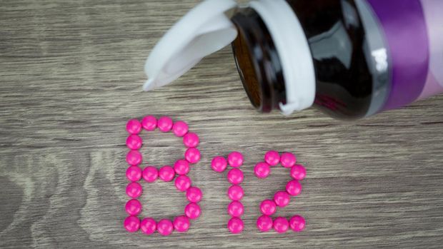Pink pills forming shape to B12 alphabet on wood background