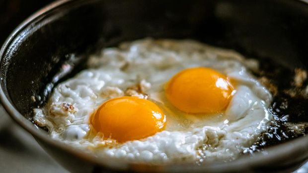 Two eggs frying in a pan with oil