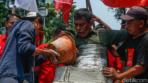 Seorang massa aksi dicor dengan semen di Jalan Medan Merdeka Selatan saat memperingati Hari Tani Nasional, Rabu (24/9/2025). Aksi ini dilakukan sebagai bentuk protes dramatik terhadap kondisi agraria negara.