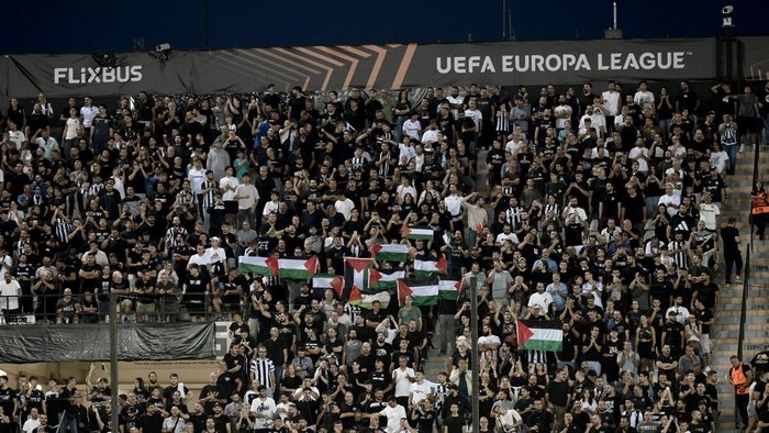 PAOK fans hold Palestinian flags during the UEFA Europa League football match day 1, between PAOK Salonika and Maccabi Tel-Aviv at the Toumba Stadium, in Thessaloniki on September 24, 2025. (Photo by SAKIS MITROLIDIS / AFP)