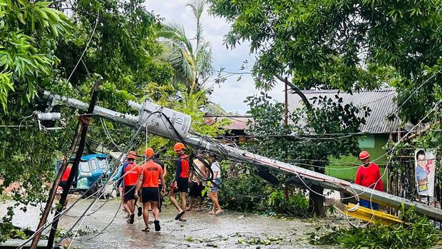This handout photo taken on September 26, 2025 and released on September 27 by the Philippine Coast Guard shows coast guard personnel walking past a fallen electric post toppled at the height of Severe Tropical Storm Bualoi, during clearing operations in Romblon town, central Philippines. The Philippines evacuated hundreds of thousands of people and confirmed at least three deaths on Friday as it faced yet another tropical storm, days after it was battered by deadly Super Typhoon Ragasa. (Photo by Handout / Philippine Coast Guard (PCG) / AFP)
