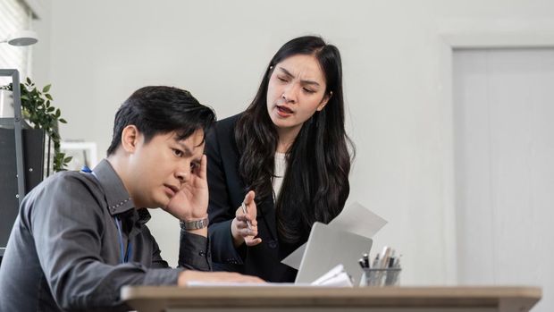 ilustrasi bos marah sama karyawan A female professional expresses concern as her male colleague shows signs of stress during a project discussion, emphasizing workplace dynamics.