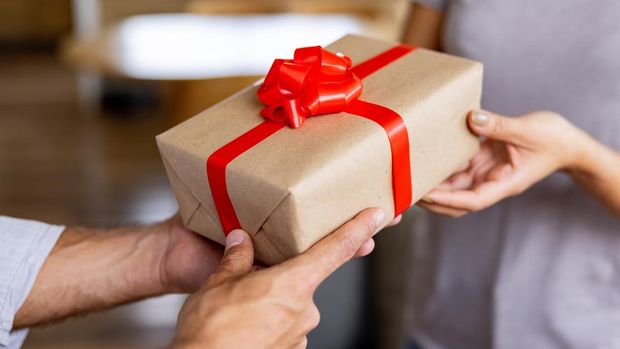 ilustrasi kado atau hadiah Close-up on a person giving an anniversary gift to another one - relationship concepts